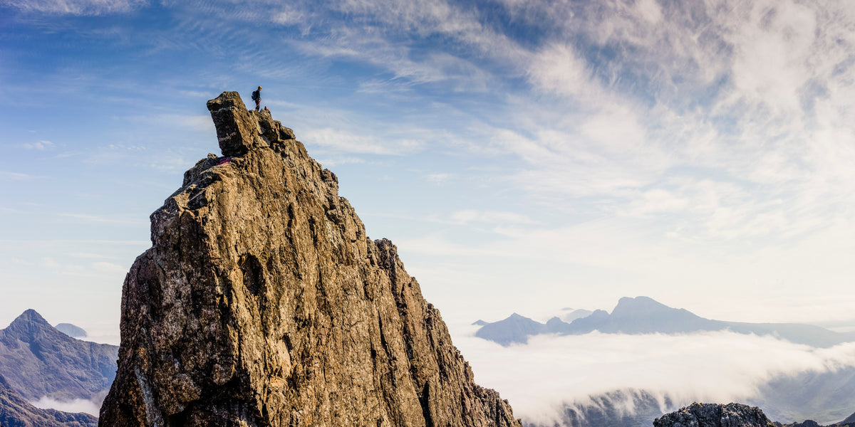 Skye Munros - Route Photos - Climber stands by the Bolster Stone on the Inaccessible Pinnacle with Sgurr nan Gillean to the left and Bla Bheinn to the right (Route 3)